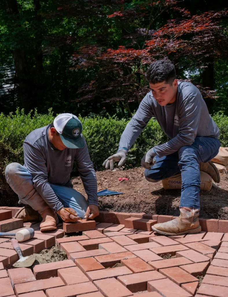 landscape workers installing brick pavers