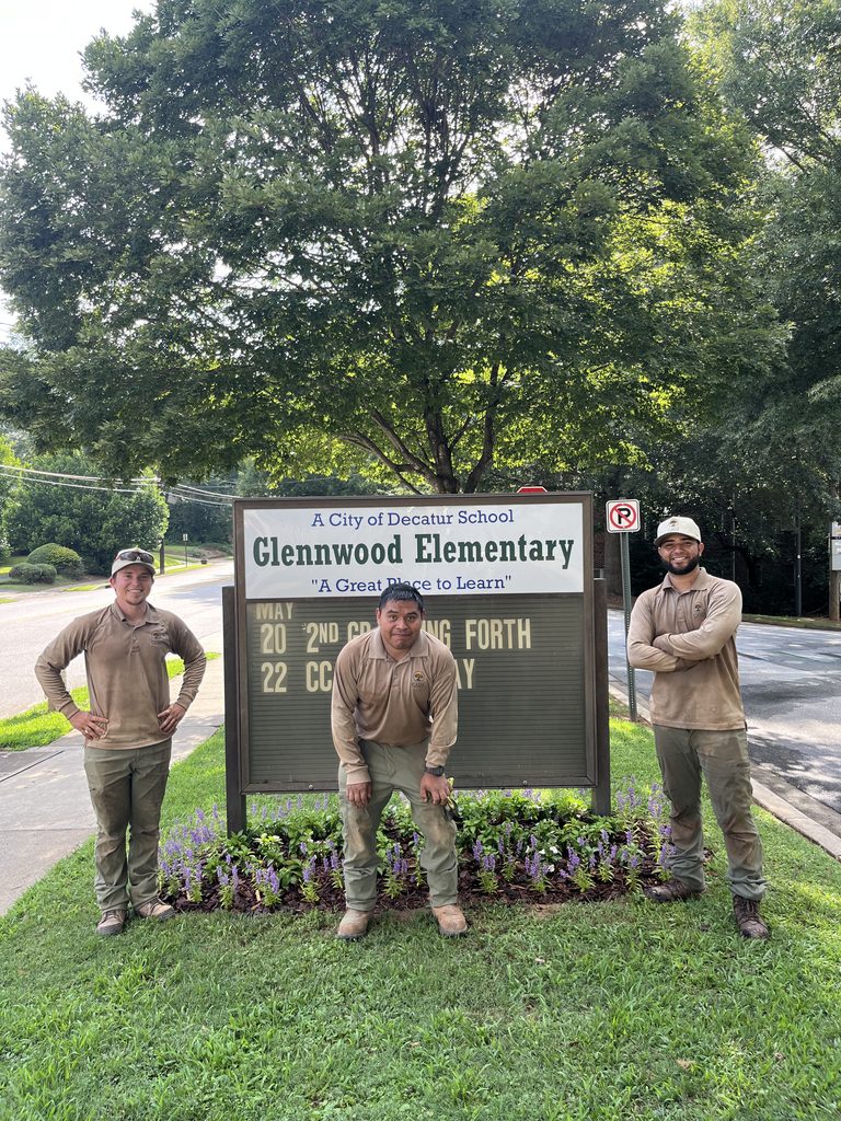 Calo Landscape team in front of school sign with new flowers